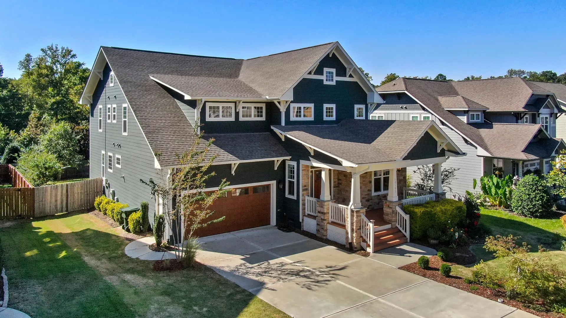 A two-story house with a front porch, landscaping, and a driveway